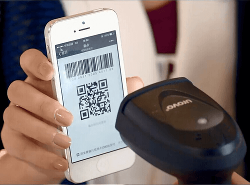 A user presents their payment QR code for scanning at a retail shop